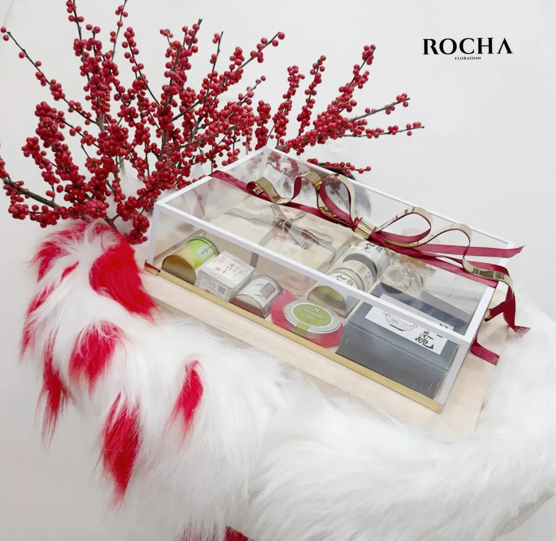 Seasonal gift set with red ilex berries, an acrylic case of teas and a gold ribbon
